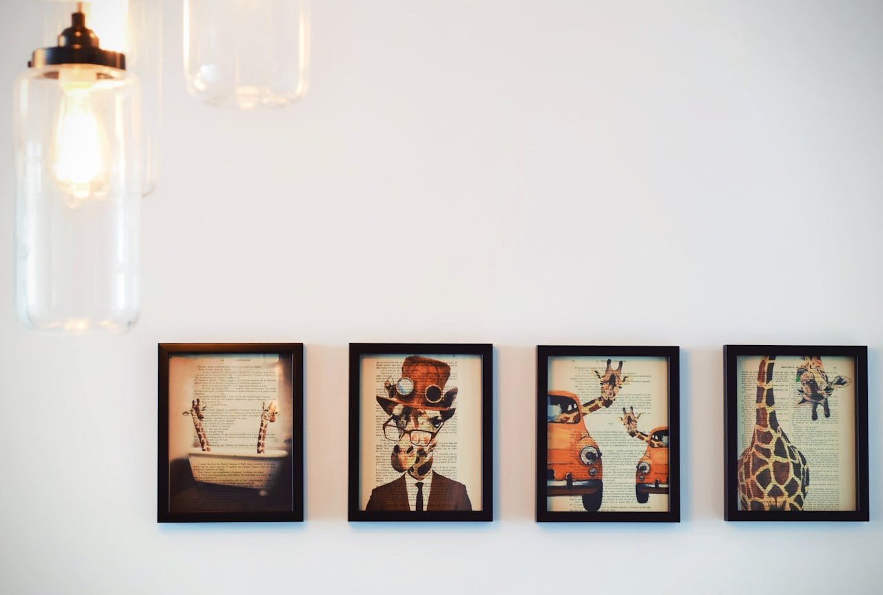 services-04 A modern interior display of four framed giraffe-themed artworks, enhanced by warm lighting.